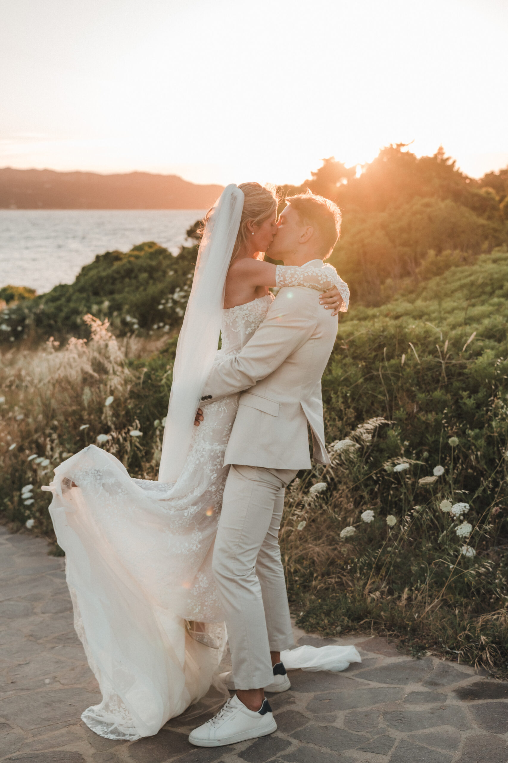 A couple at sunset, the bride’s veil in the wind